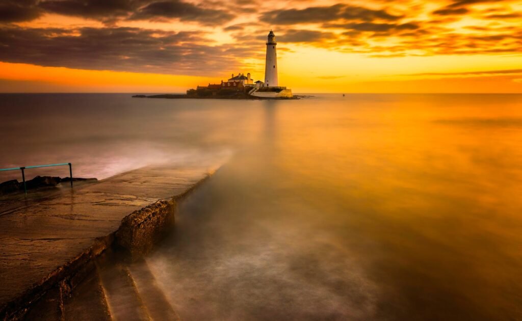 scenic view of a lighthouse on the sea during sunset